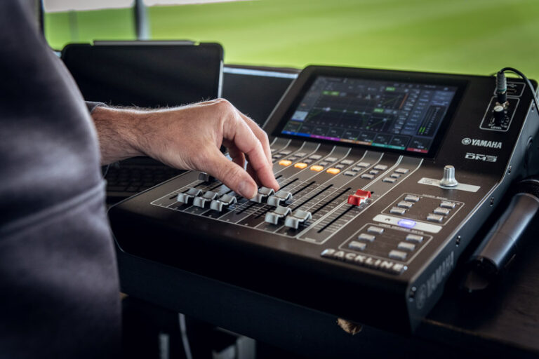 Mengpaneel in de ruimte van de live omroeper, met uitzicht op het groene voetbalveld.