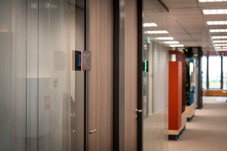 Roombooking panels op een rijtje op de gang van het kantoor.