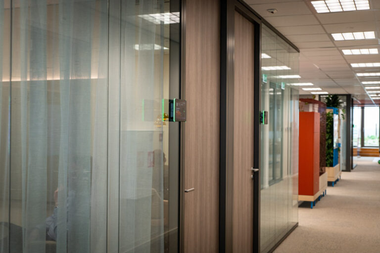 Roombooking panels op een rijtje op de gang van het kantoor.